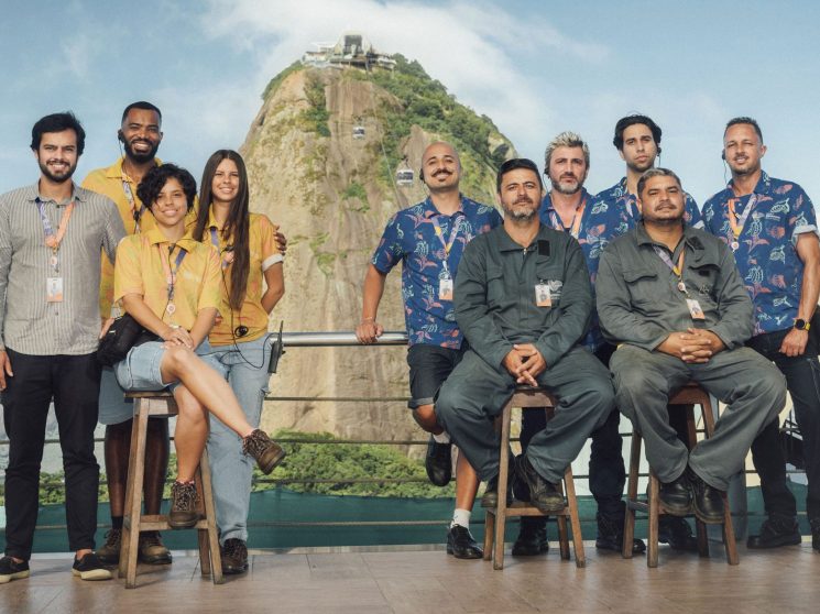 Group of cable car team members posing together with Sugarloaf mountain visible in the background