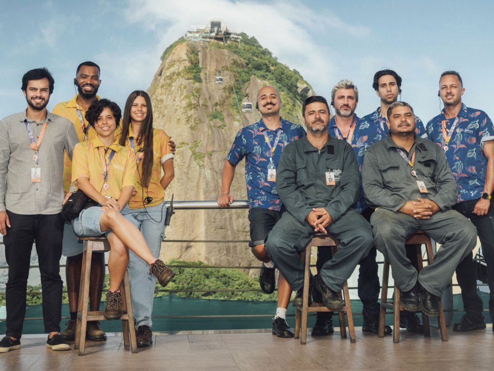 Group of cable car team members posing together with Sugarloaf mountain visible in the background