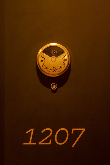 Hotel room door numbered 1207 with ornate brass door knocker featuring decorative face design