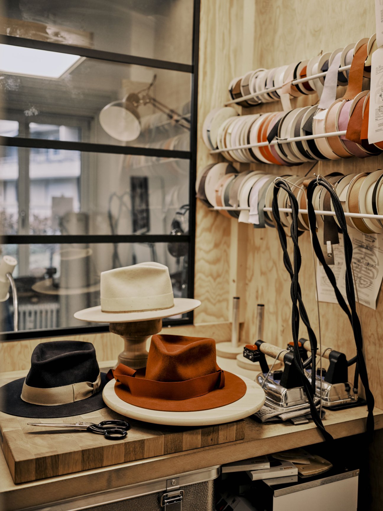 Onkai Heiwa hat-maker's studio with fedoras on display and ribbon spools organized on wall shelves.
