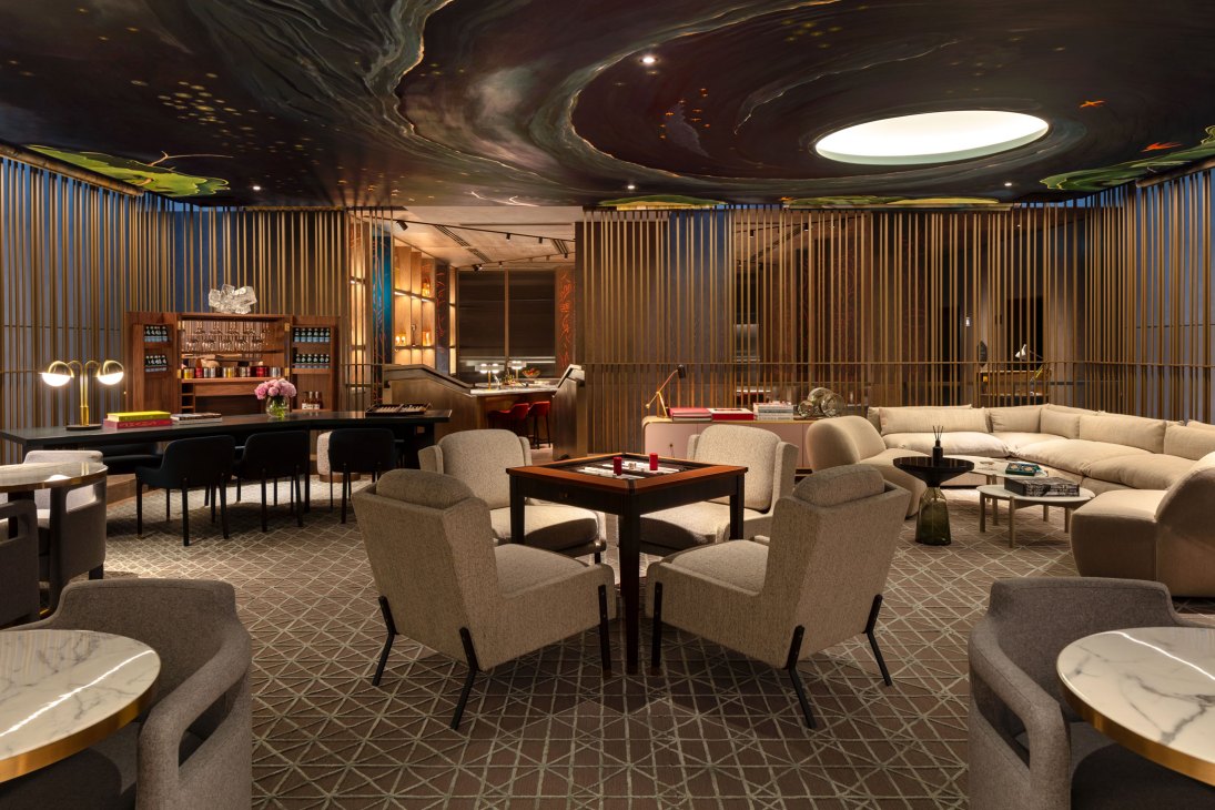 Elegant hotel lounge with dramatic painted ceiling, vertical wood paneling, grand piano, and neutral seating areas