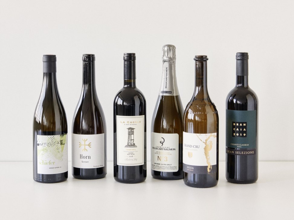 Six wine bottles displayed against a neutral background, including Schiefer, Horn, La Caccia, Billecart-Salmon, Heida, and Brancaia varieties.