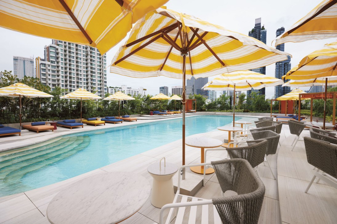 Rooftop terrace and pool at The Standard Bangkok with yellow striped umbrellas and city skyline views