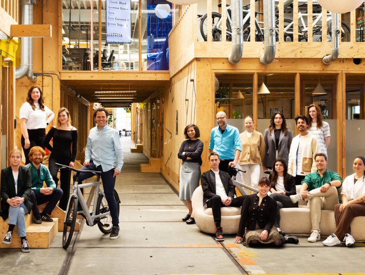 VanMoof team members posing in their modern wooden Amsterdam headquarters with bicycles and industrial design