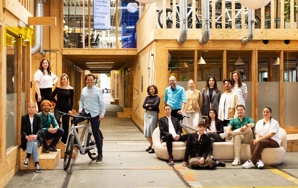 VanMoof team members posing in their modern wooden Amsterdam headquarters with bicycles and industrial design