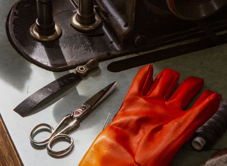 Red leather glove on a workbench beside scissors and craft tools.
