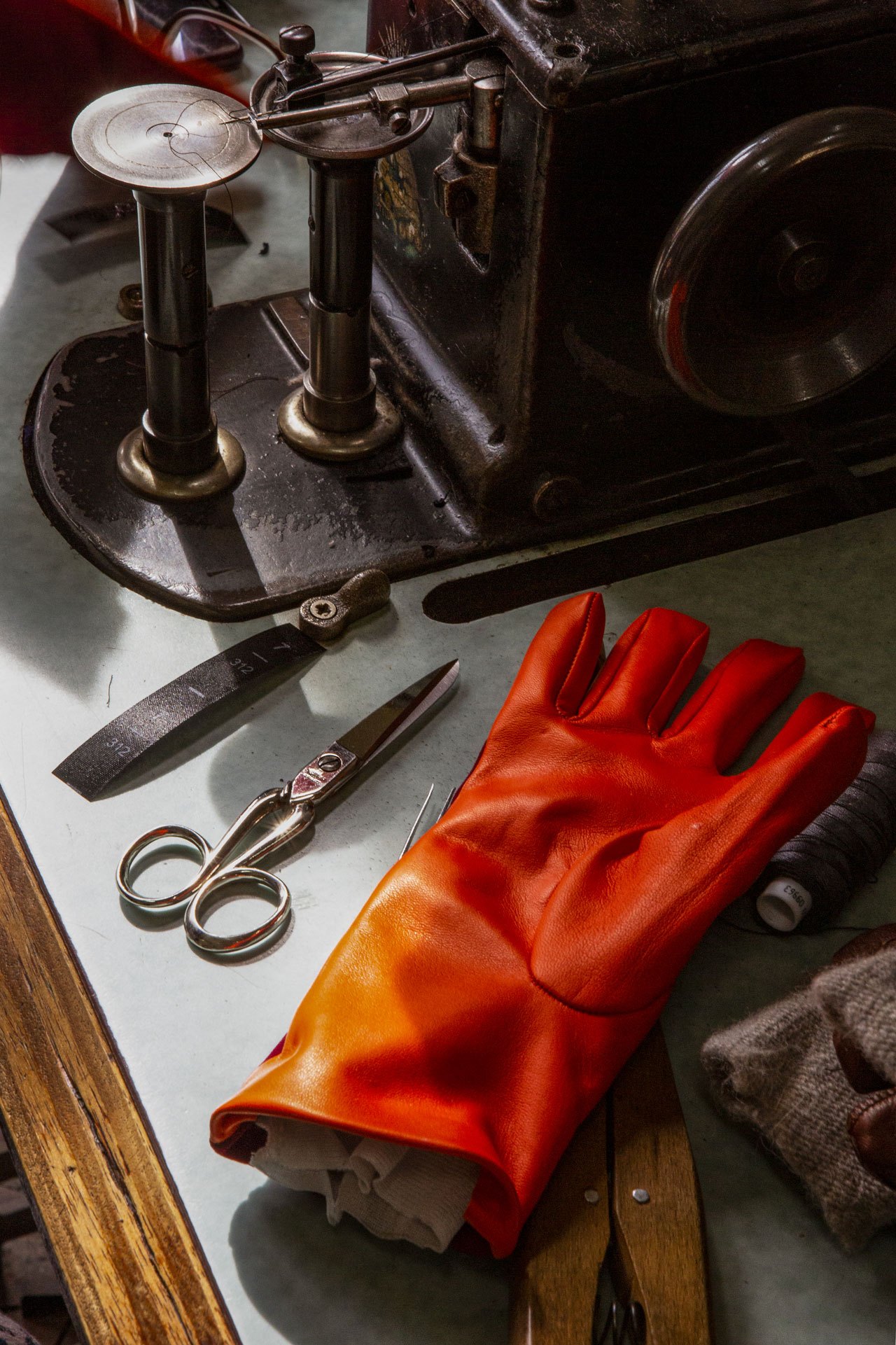 Red leather gloves displayed alongside vintage crafting tools at Omega glove-maker in Naples.