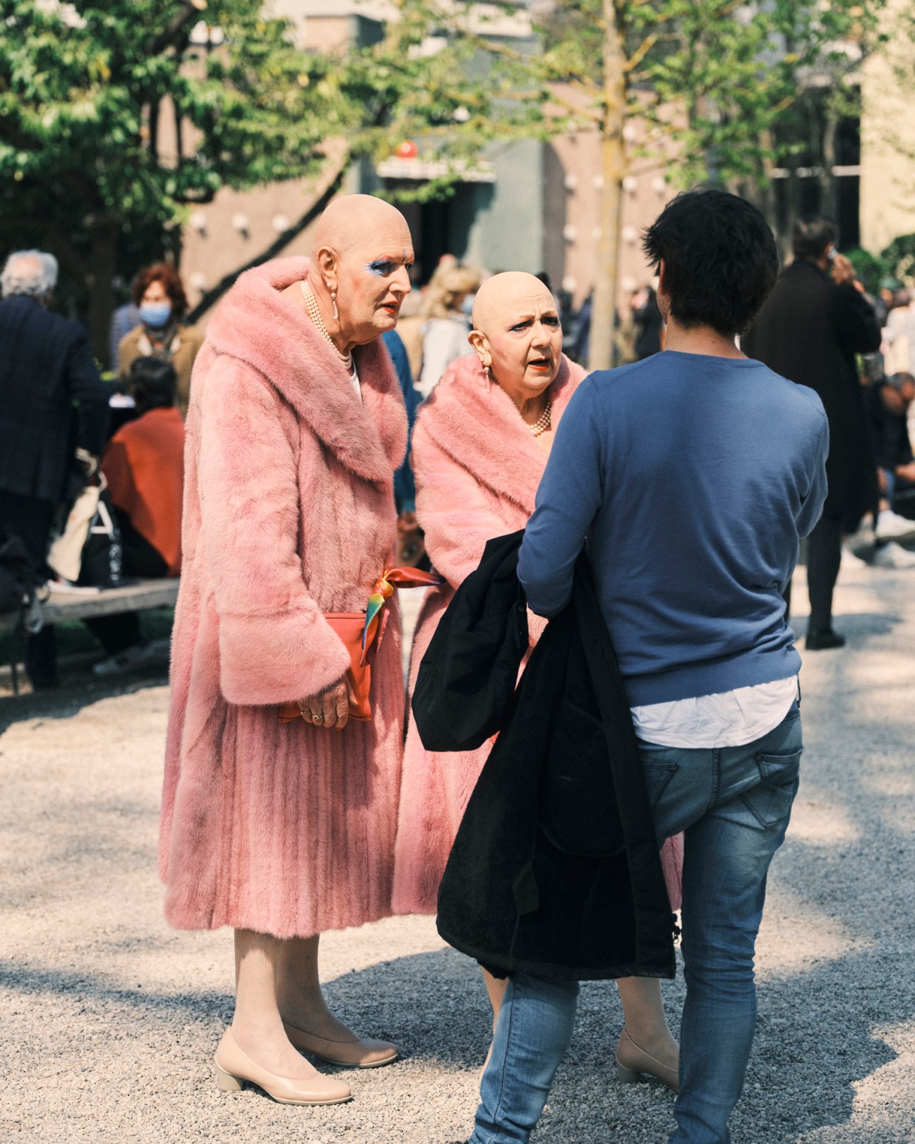Artists Eva & Adele in pink fur stoles converse with a visitor at the Venice Biennale.