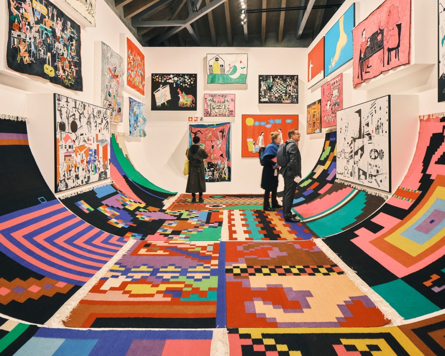 Colorful geometric patterned installation with visitors viewing artworks on white walls