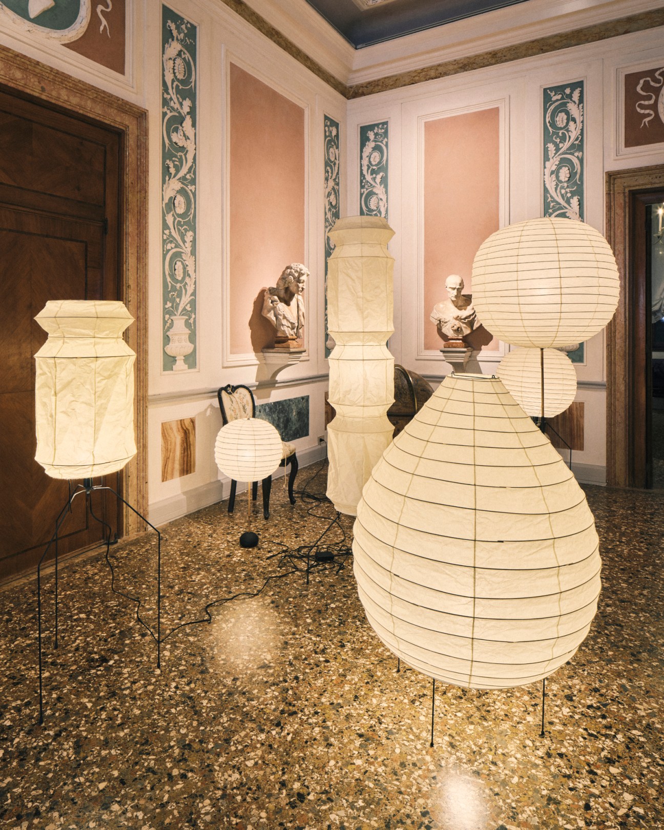 Isamu Noguchi light sculptures displayed in a classical gallery space with busts on pedestals
