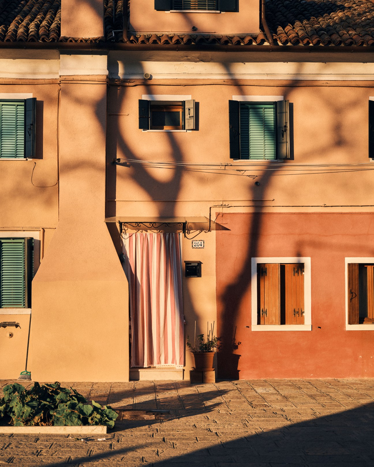 Colorful houses along Burano canal in warm pastel shades of pink, yellow and blue