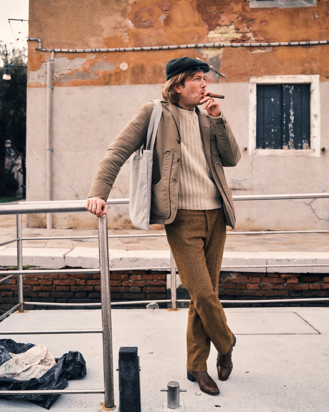 Gondolier in striped shirt and hat standing beside his traditional black gondola