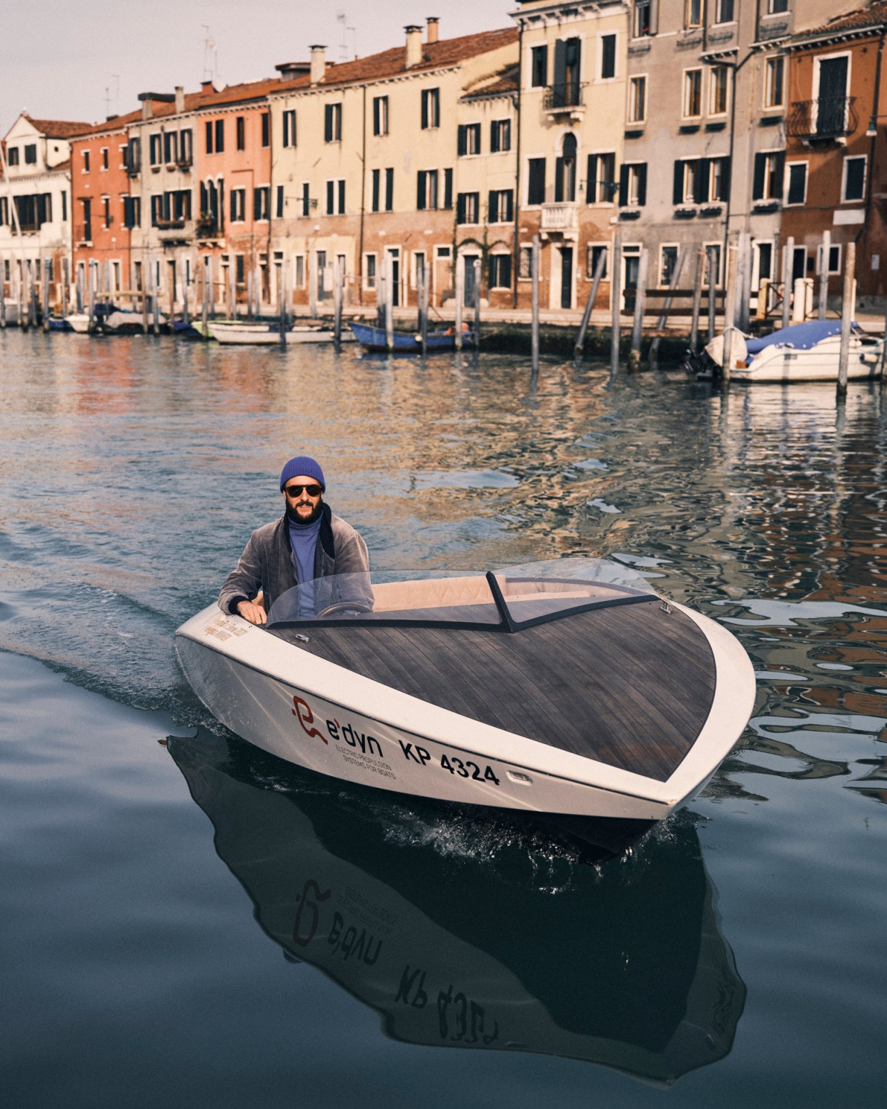 Francesco Pannoli in sunglasses and bomber jacket steering his electric boat
