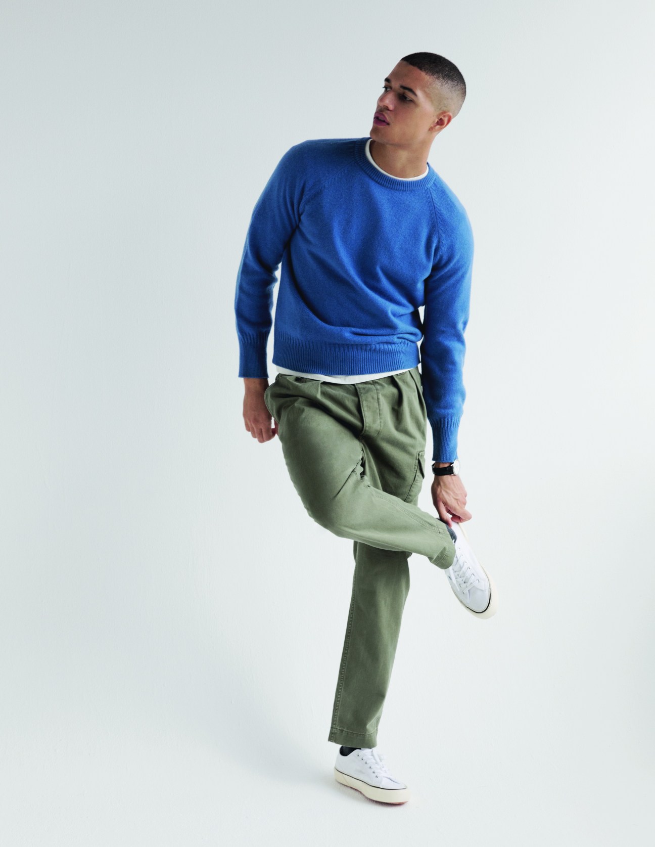 Model in relaxed sportswear with blue jumper, green trousers and white trainers