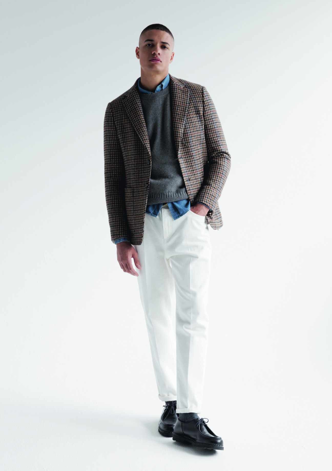 Model in classic autumn styling with navy blazer, cream jumper and dark jeans