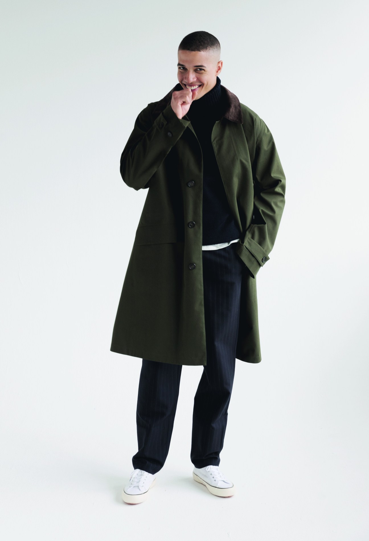 Model wearing elegant camel coat with navy knitwear and dark trousers