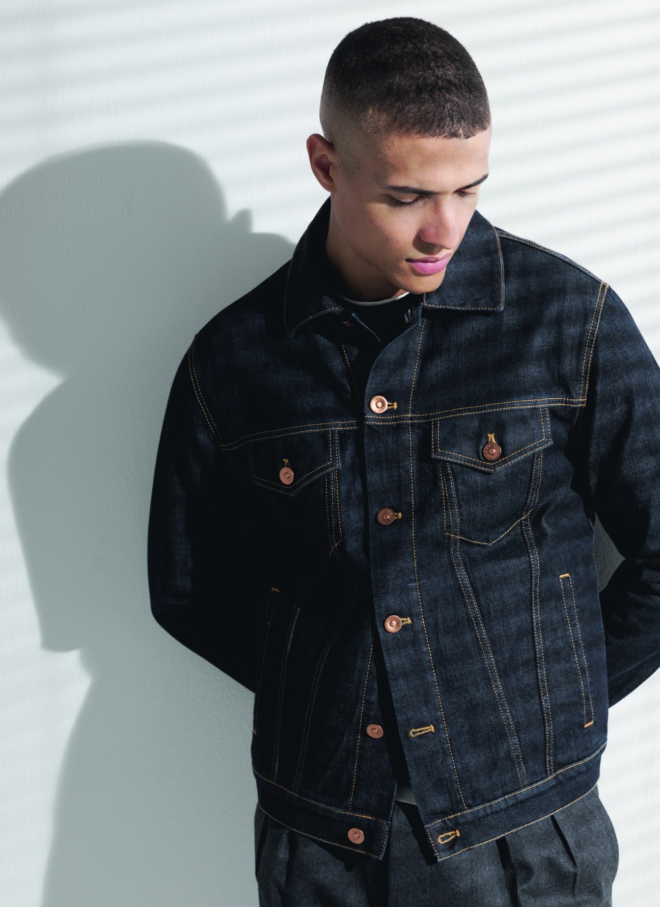 Model in textured navy jacket with camel-coloured jumper and dark trousers
