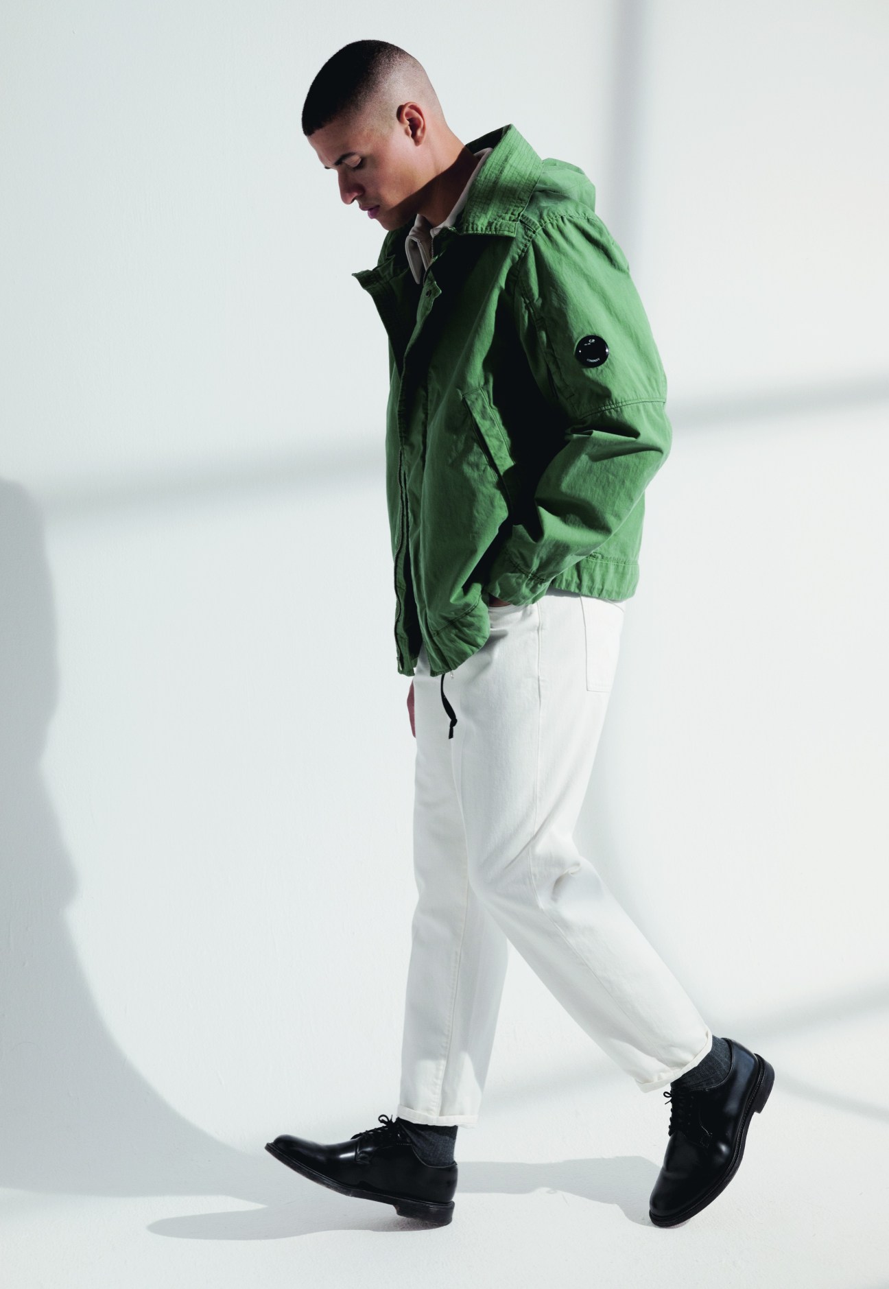 Model in green CP Company jacket, white trousers and black Church's shoes.