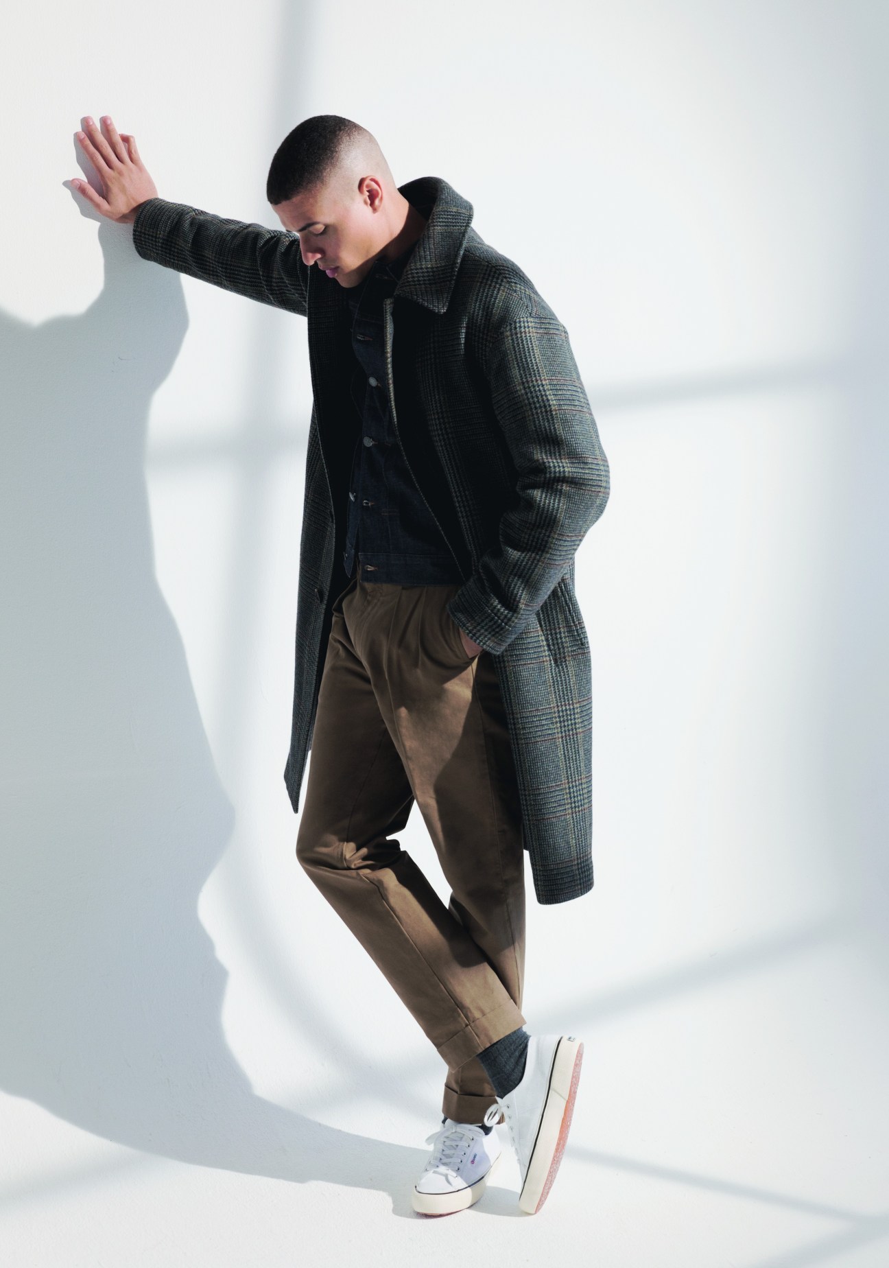 Model wearing luxurious layered look with camel coat, navy jacket and white trainers