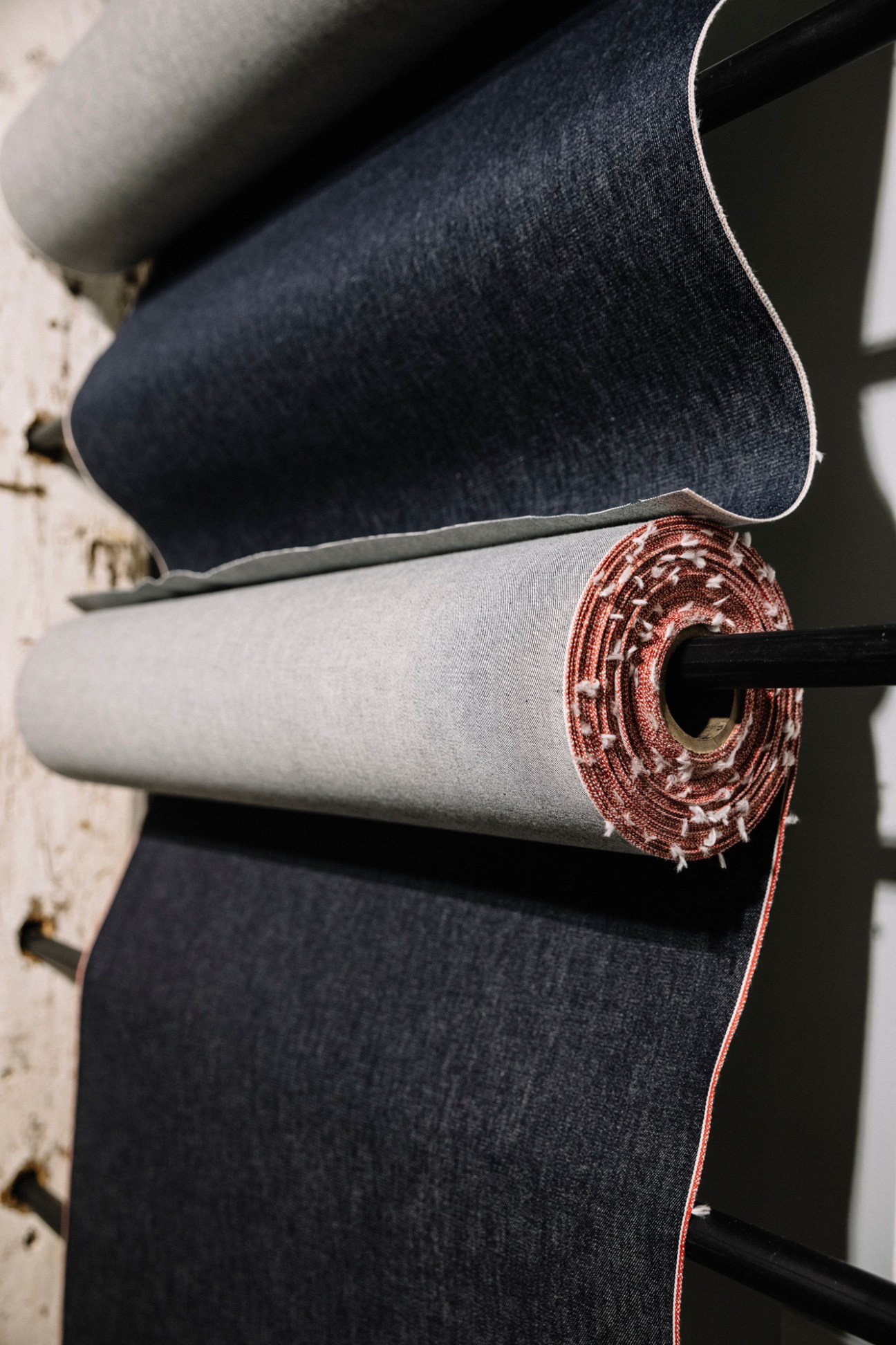 Rolls of denim fabric stacked in a textile mill with light and dark colored materials