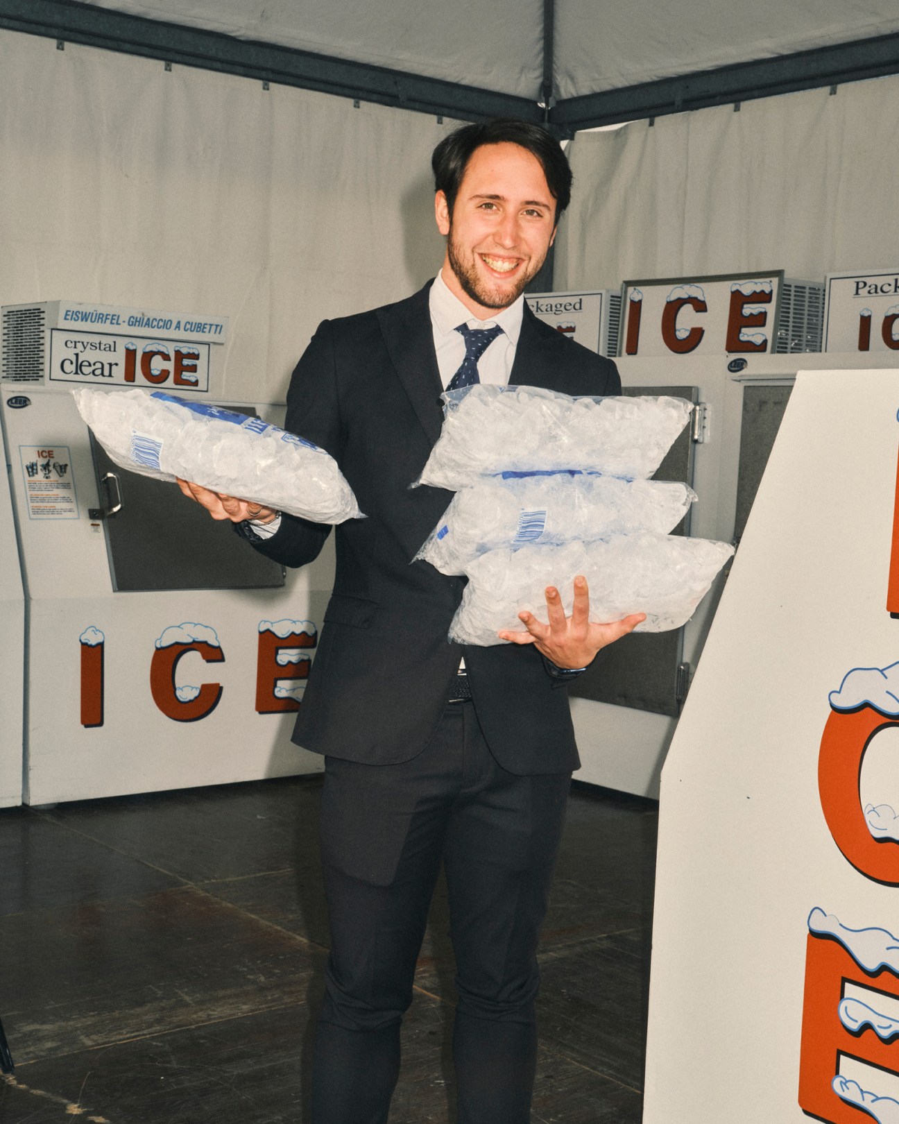 Man in suit holding bags of ice at Vinitaly trade fair ice station