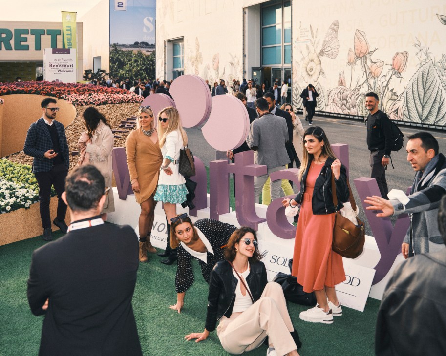 People posing and socializing around large pink letter sculptures at Vinitaly wine trade fair