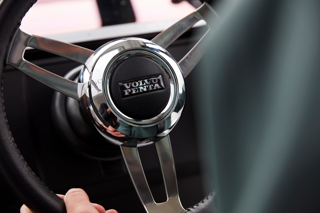 Close-up of a chrome steering wheel with black Volvo Penta logo in the center hub of a boat