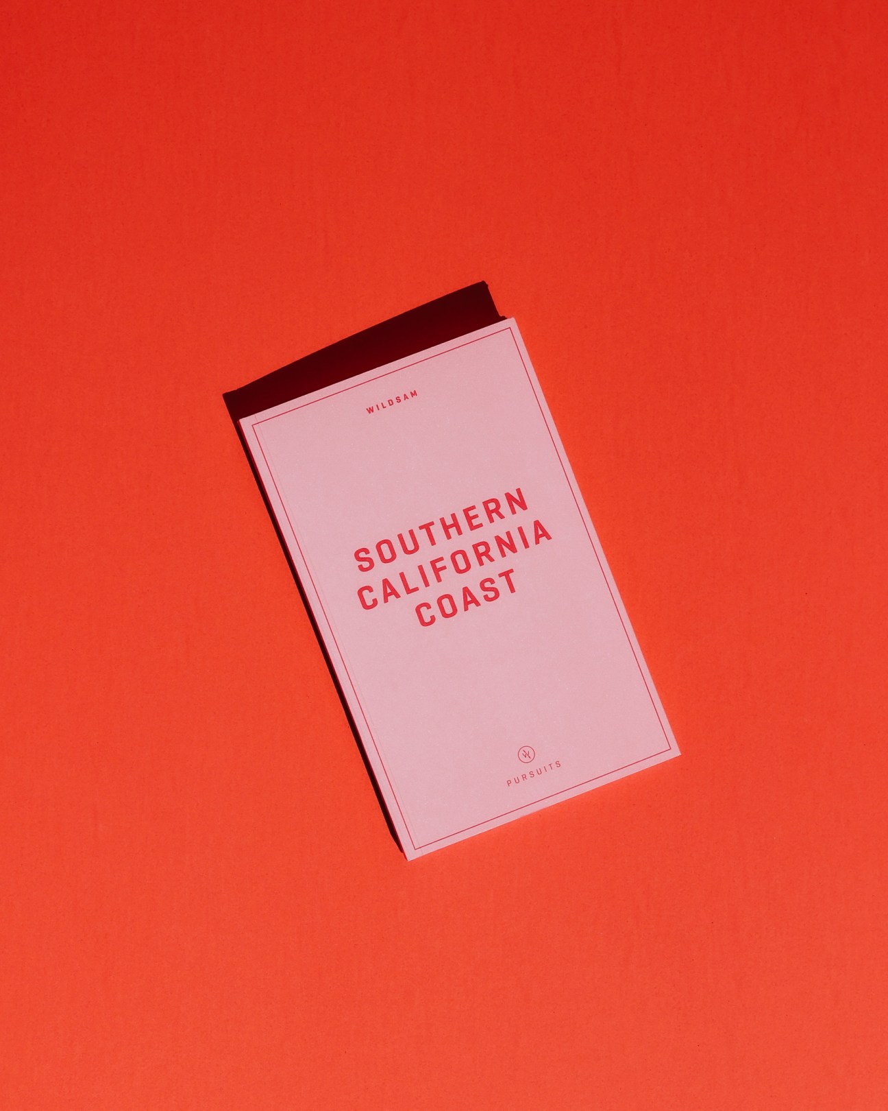 Wildsam travel guide for Southern California with pink cover and dark red spine against red background.