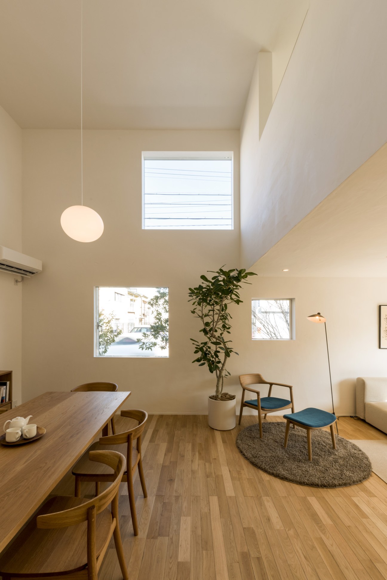 Bright interior of a Muji Window House showing dining area with wooden table and chairs, multiple windows providing natural light, and minimalist furnishings.
