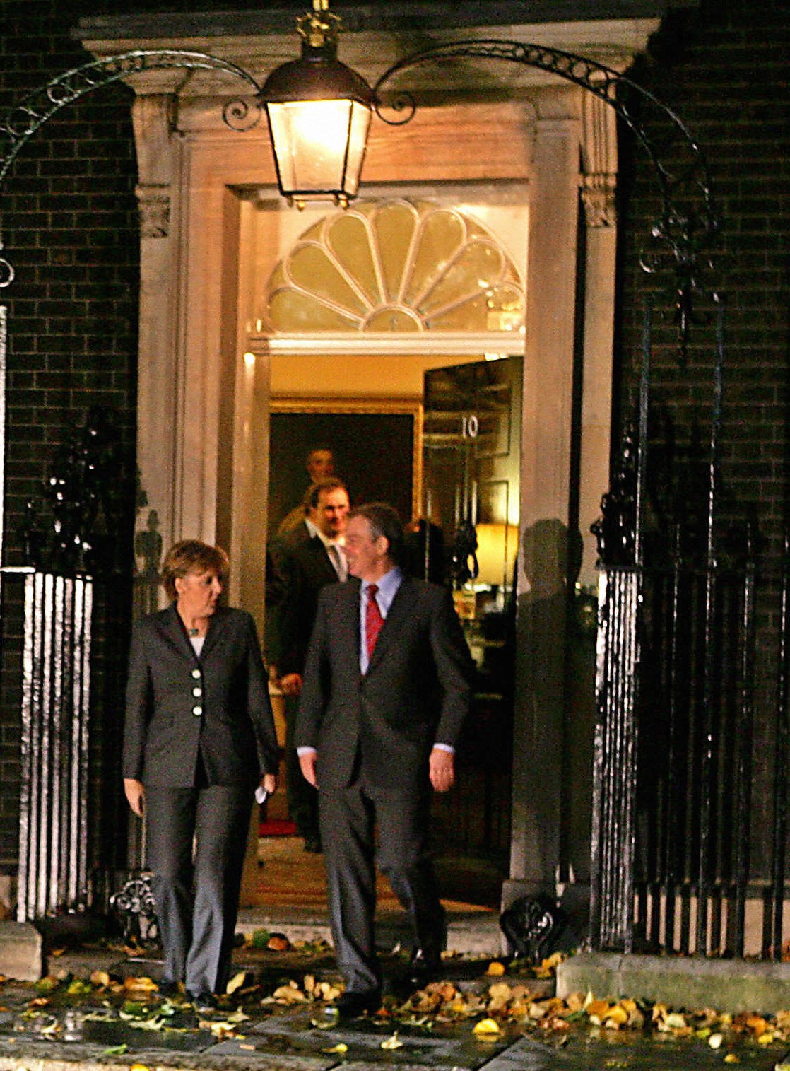 Two people in business attire walking outside an ornate building entrance with classical architecture at night