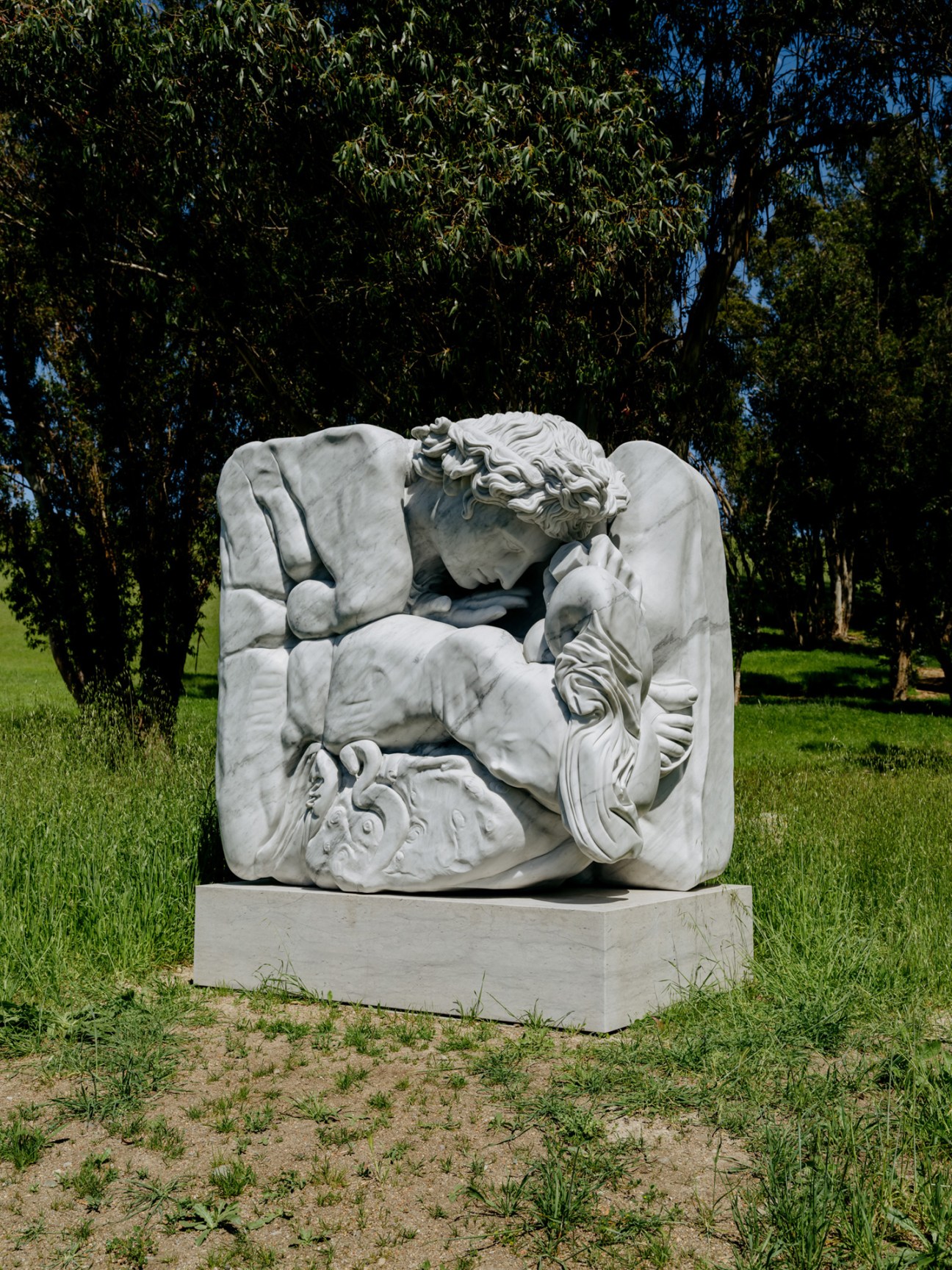 White marble sculpture of a reclining classical figure on grass surrounded by eucalyptus trees at Donum Estate.