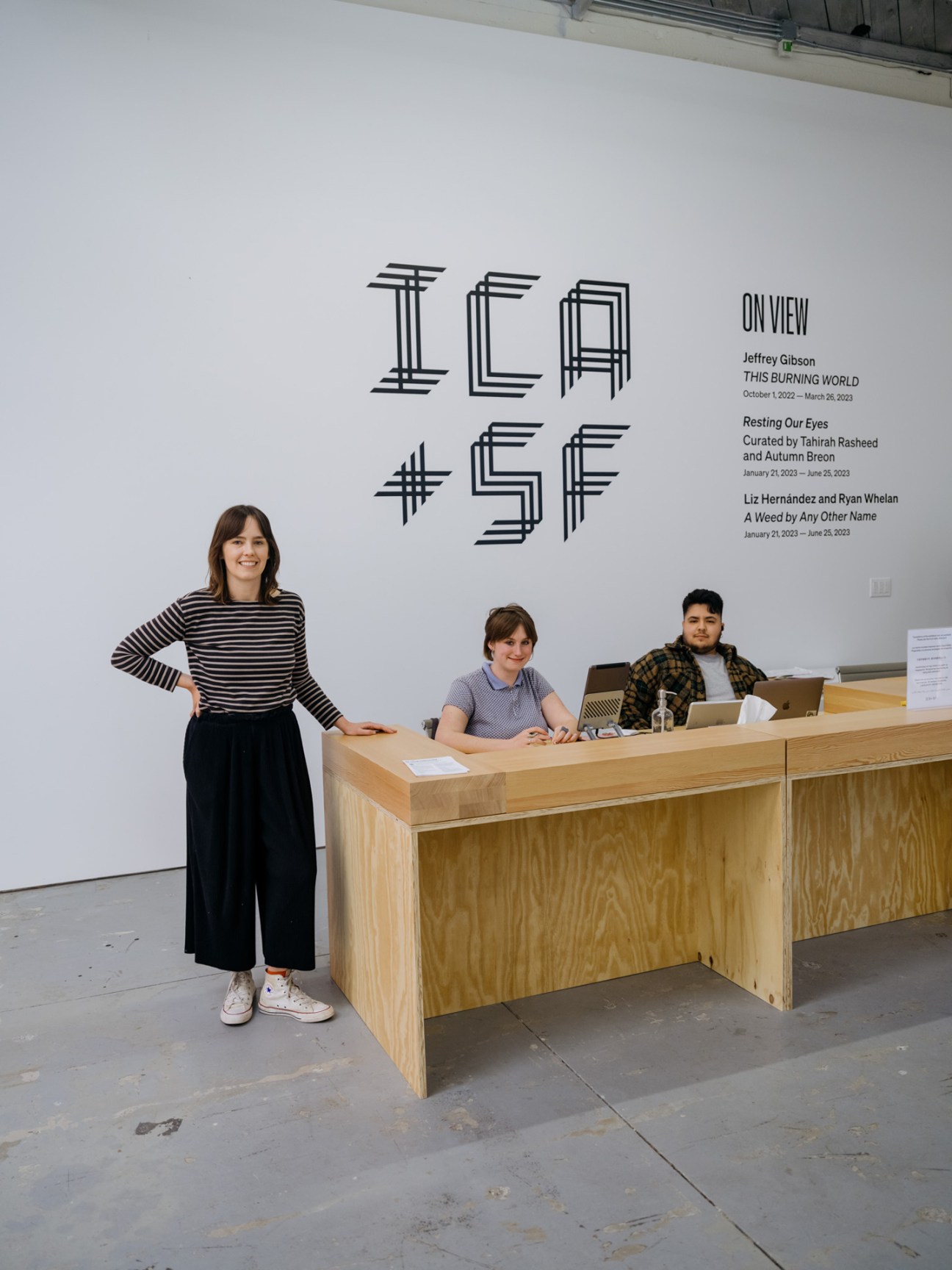Gallery reception desk at ICA San Francisco with staff members and geometric wall signage.