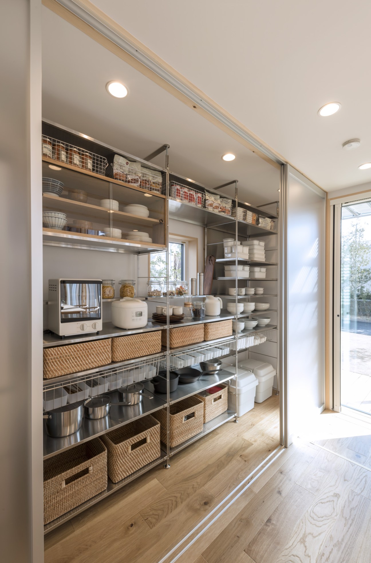A Muji House kitchen with open shelving displaying white dishes and kitchen appliances including a microwave and rice cooker.