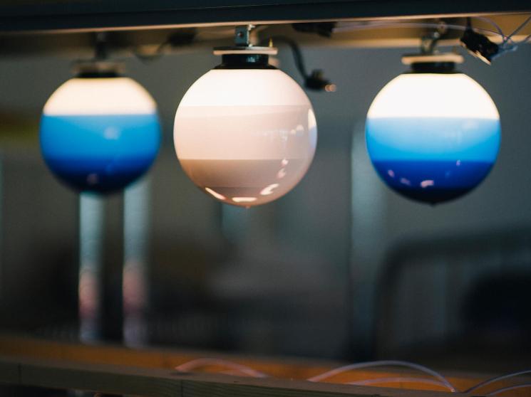 Rows of glowing spherical pendant lights in blue-to-white and pink-to-white gradients mounted on metal rails.