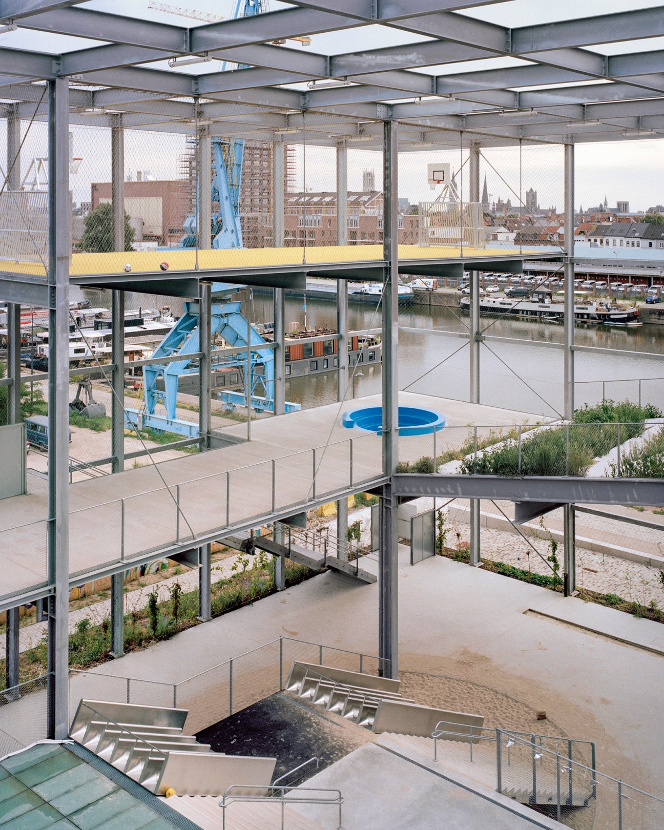 Interior view of Melopee school in Ghent showing metal grid structure and transparent design creating an open, light-filled educational space.
