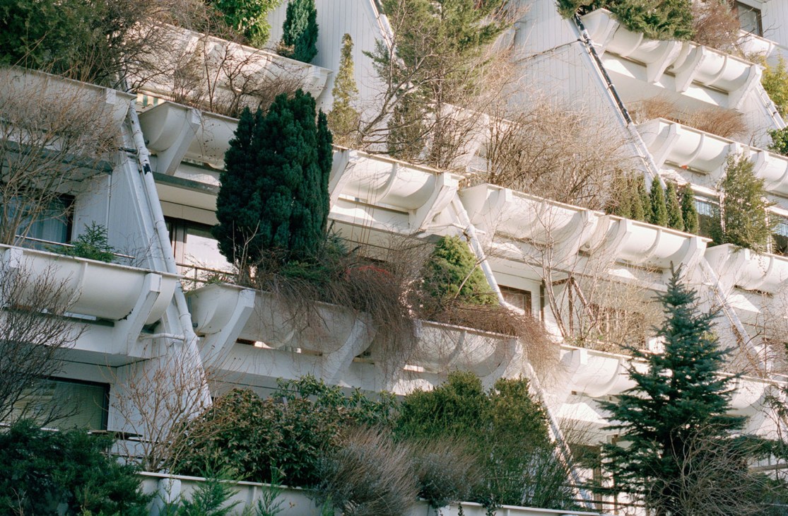 Terraced balconies with vegetation and white concrete beams at the Alterlaa housing complex in Vienna