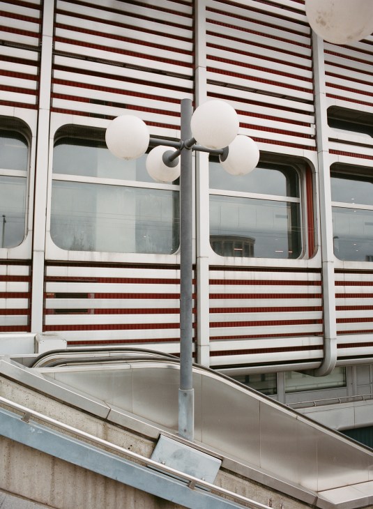 Exterior detail of the International Congress Centre showing horizontal striped aluminium cladding in white, red and black with a modern street lamp