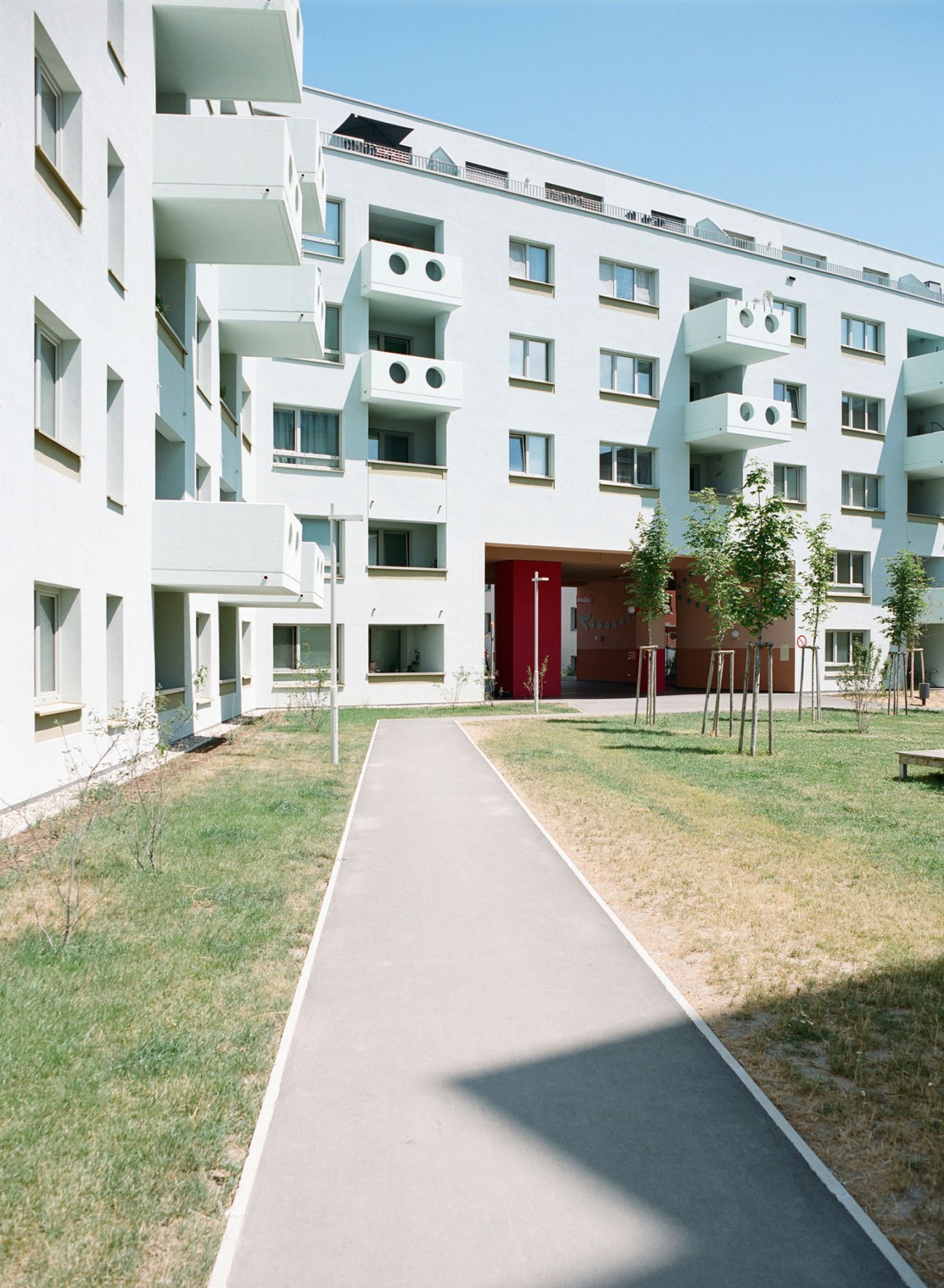 Modern white apartment building with balconies and walkway at Vienna's Wildgarten Gemeindebau development