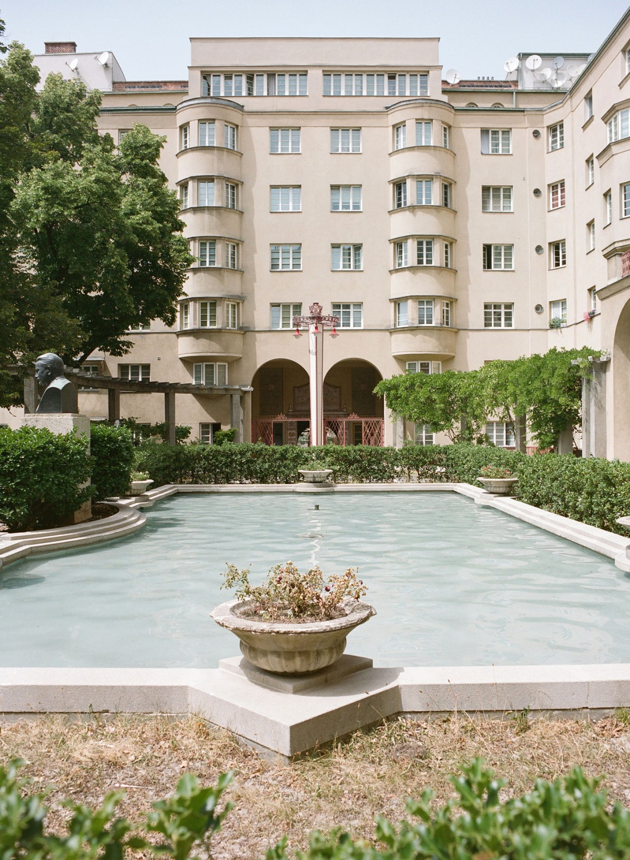 Cream-colored modernist apartment building with curved balconies and arched ground floor entrance