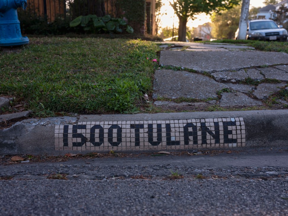 Historic blue and white mosaic tile street sign embedded in Houston curb showing street name