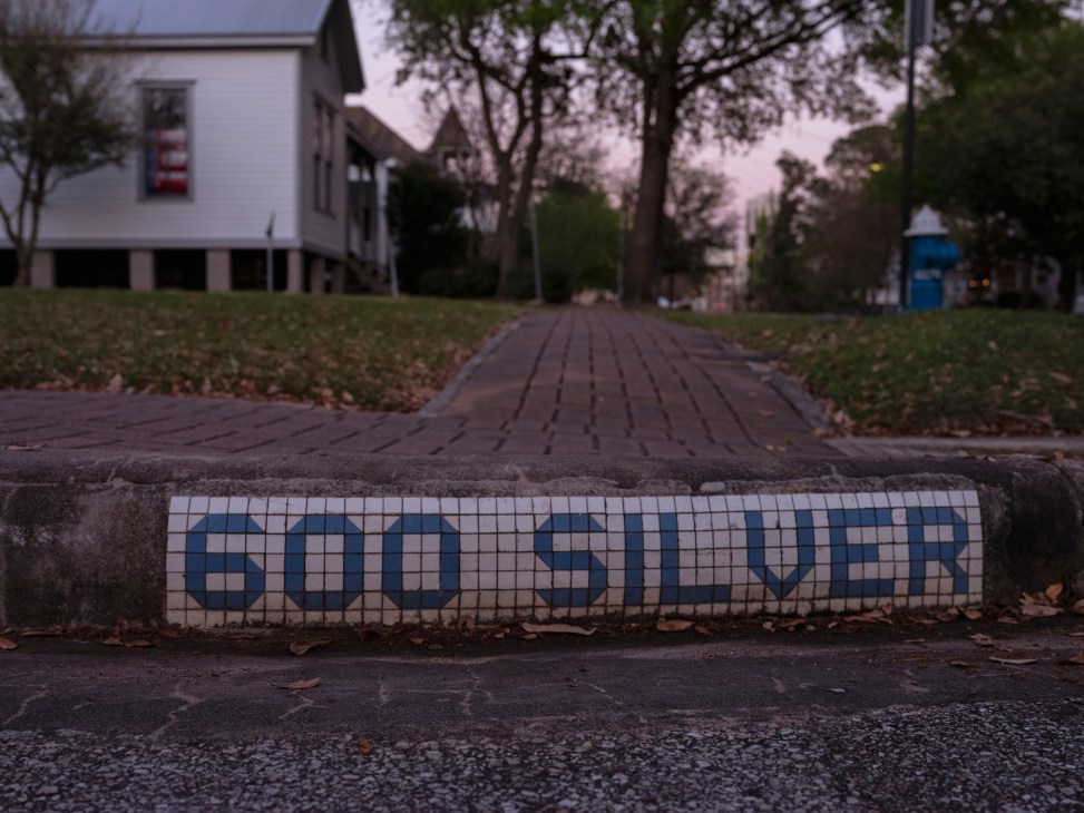 Blue and white mosaic tile street sign reading 'GOO SILVER' embedded in Houston sidewalk