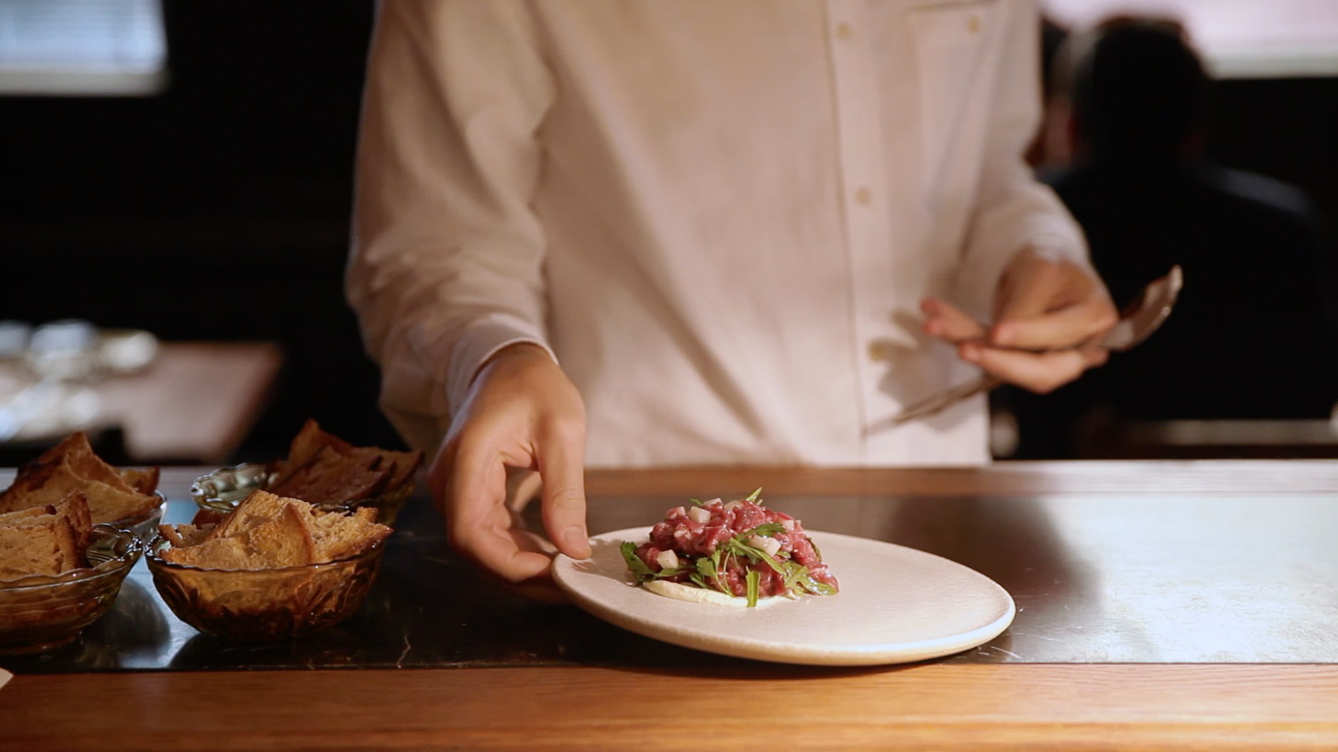 A chef serving food at a restaurant.