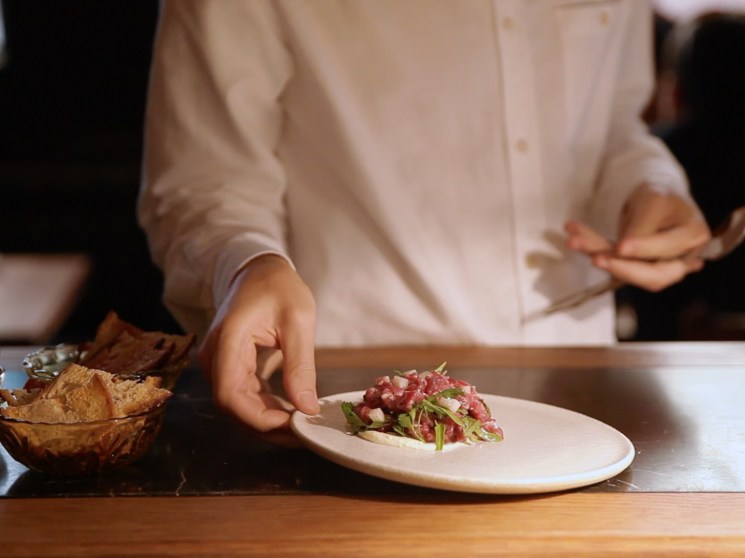 A chef serving food at a restaurant.