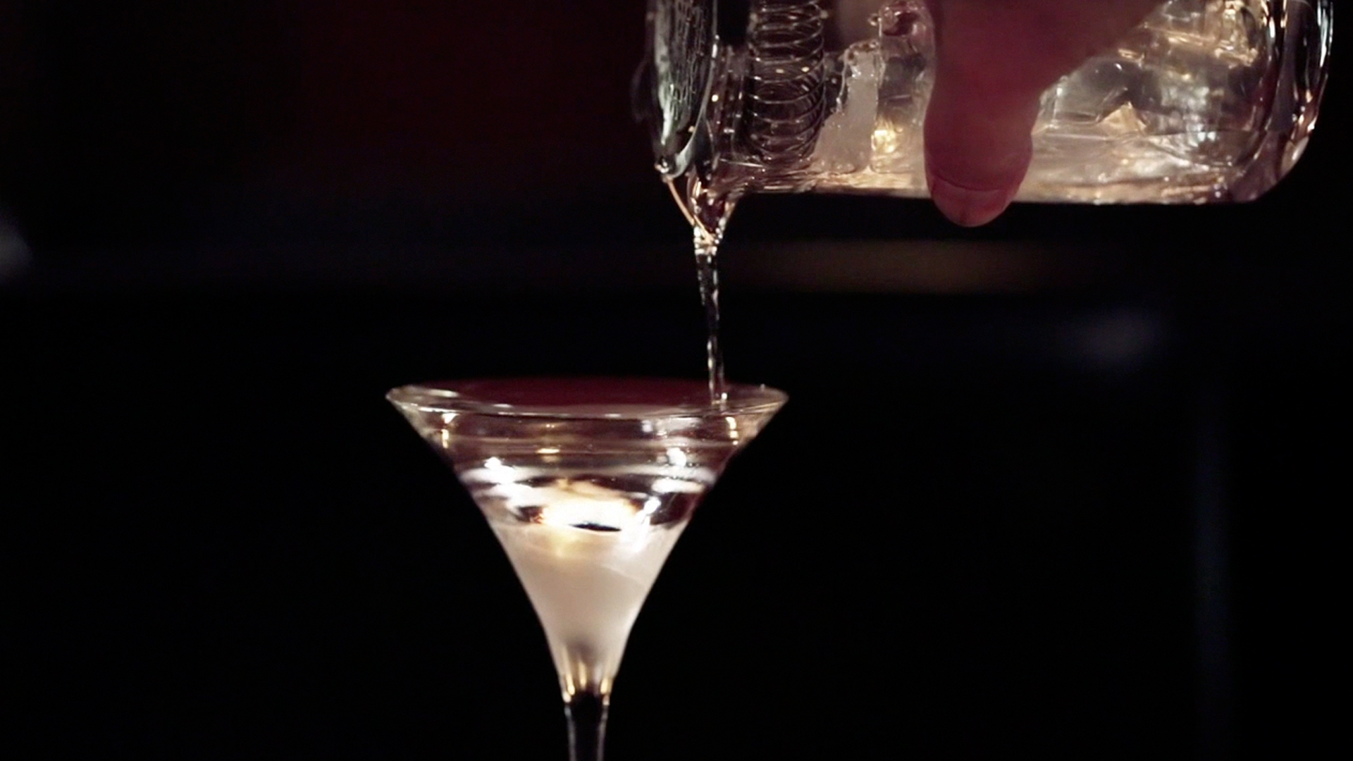 pouring drink into a cocktail glass