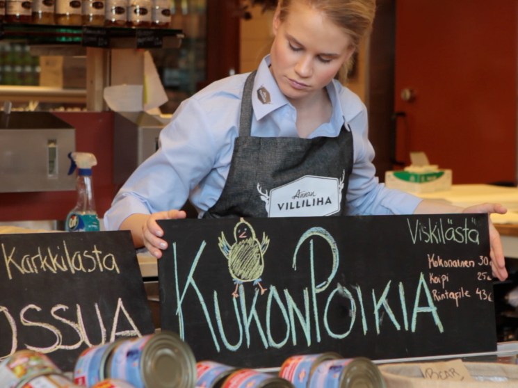A woman arranging blackboard signs at a market.