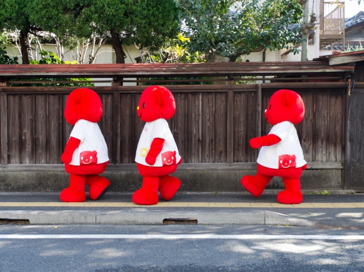 Japanese mascots walking in the street.