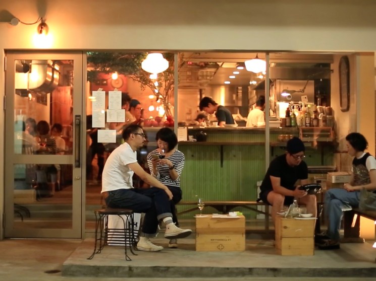 People sitting in front of a bar in Tokyo.