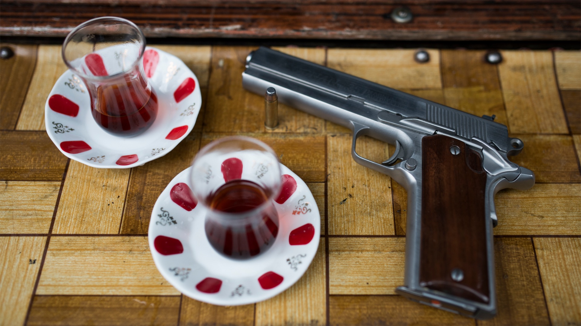 Gun lying on the table with cups of tea.