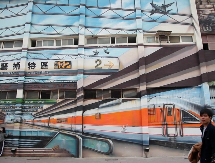 people next to a building with train graffiti