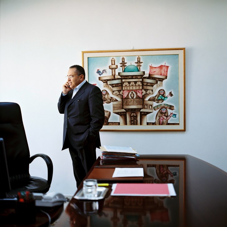 Taoufik Habaieb, founder of TH Com PR firm, stands in his office beside a desk and framed artwork.